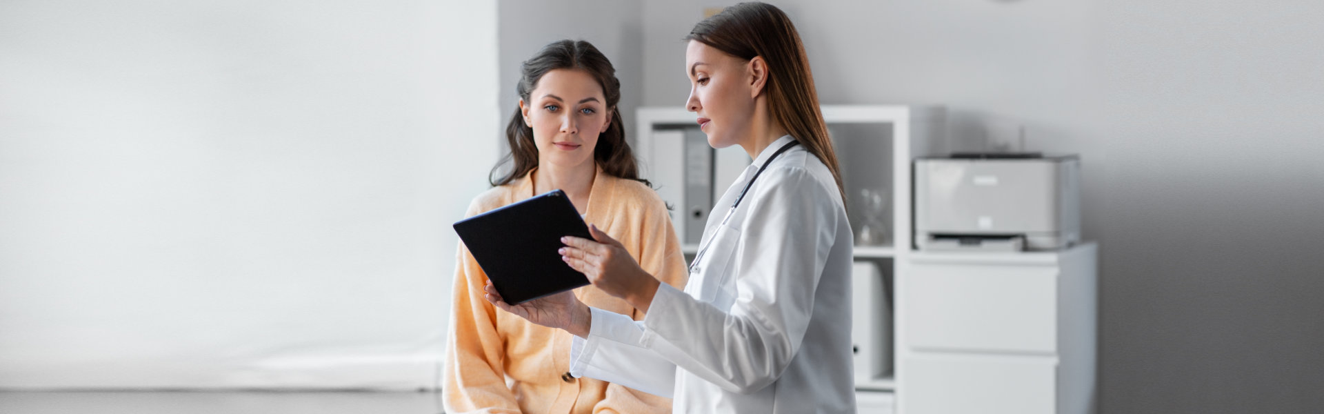 medicine, healthcare and people concept - female doctor with tablet pc computer talking to woman patient at hospital